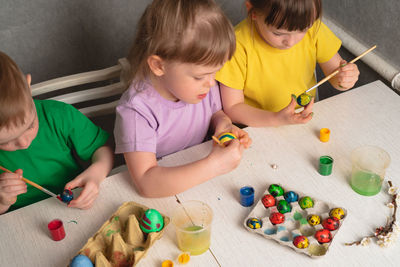 Children color eggs with food coloring. brother and sisters painting easter eggs.