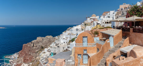 Panoramic view of buildings by sea against blue sky