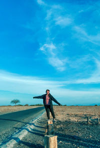 Full length of woman standing against blue sky