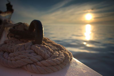 Close-up of rope tied to boat against sky during sunset