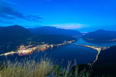 Scenic view of silhouette mountains by lake against blue sky at night