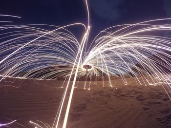 Person making wire wool at beach against sky
