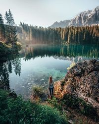 Rear view of man standing by lake