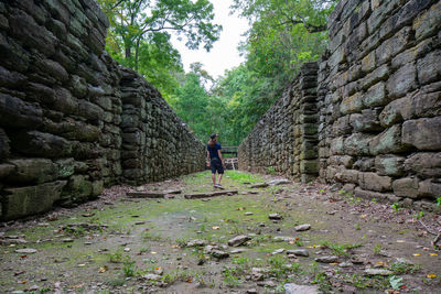 Rear view of person walking on stone wall