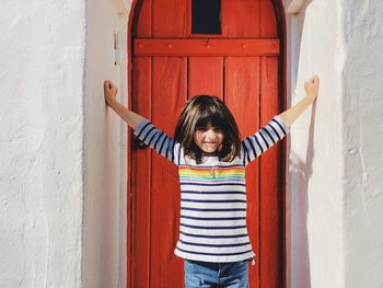Portrait of girl standing against door