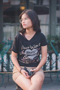 Indonesia teenager with glasses sitting in public place