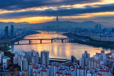 Bridge over river with buildings in background at sunset