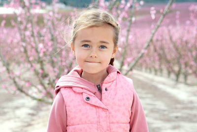 Portrait of girl standing by pink flower