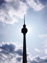 Low angle view of communications tower against cloudy sky