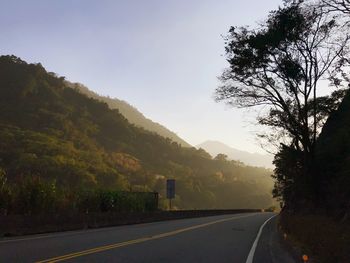 Road by trees against sky