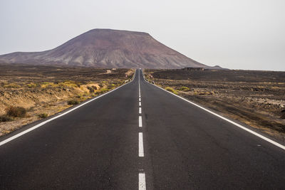 Road leading towards mountain against sky