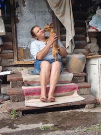 Mature woman holding dog while sitting in steps