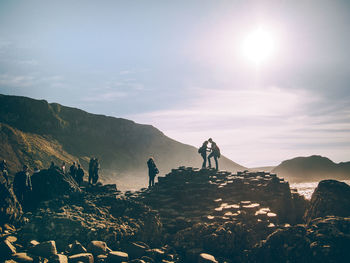 People standing on rocks by sea