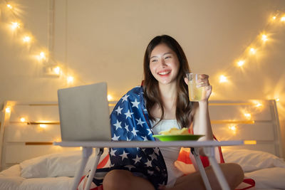 Young woman using smart phone while sitting in restaurant