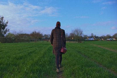 Rear view of woman walking on grassy field