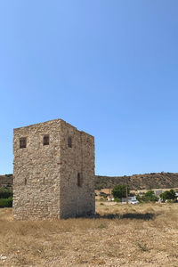 Old building on field against clear blue sky