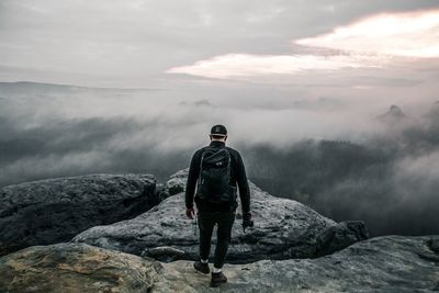 Rear view of man standing on rocks against mountain