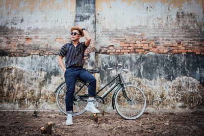 Man sitting on bicycle against wall in city