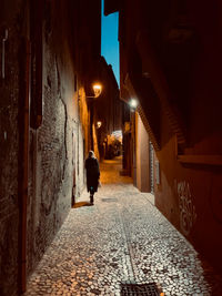 Rear view of woman walking on footpath amidst buildings