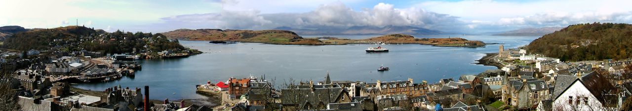 Panoramic view of sea and buildings against cloudy sky