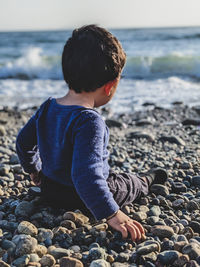 Side view of boy sitting at beach