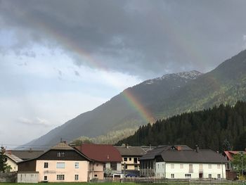 Scenic view of rainbow over houses and mountains against sky
