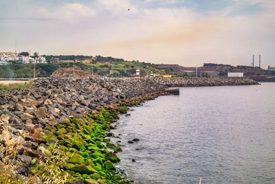 Scenic view of sea by buildings against sky