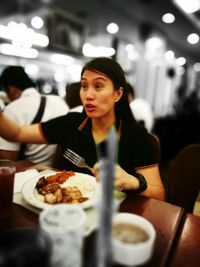 Young woman eating food in restaurant