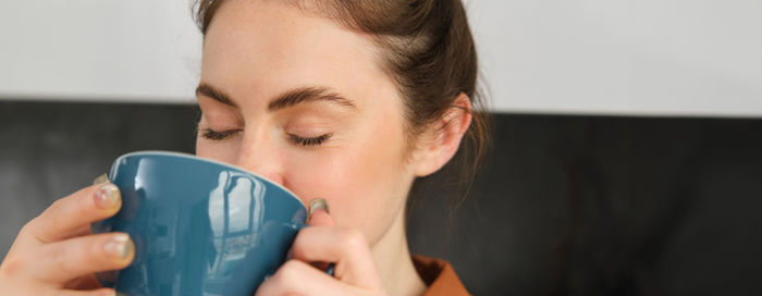 Close-up of young woman drinking coffee at home