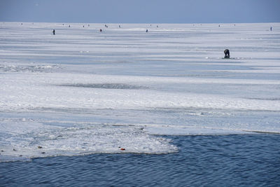 High angle view of people fishing on frozen lake