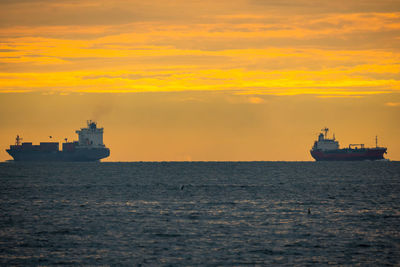 Ship sailing on sea against sky during sunset