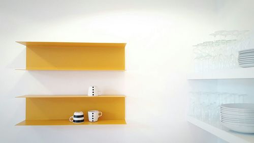 Plates with cups on shelves in kitchen