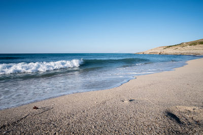 Scenic view of beach against clear blue sky