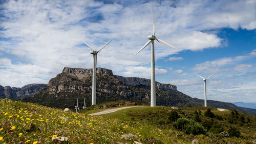 Wind turbines on field against sky