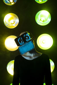 Woman with head cocked wearing vr glasses in front of neon lighting