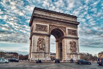 Low angle view of triumphal arch against cloudy sky