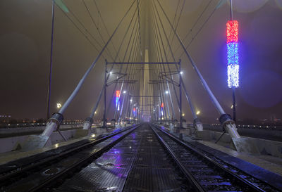 Illuminated railroad bridge against sky at night