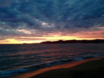 Scenic view of sea against dramatic sky during sunset