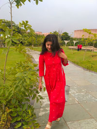 Portrait of young woman standing against plants