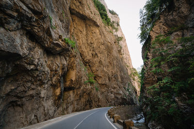 Road amidst rocky mountains and canyon against sky