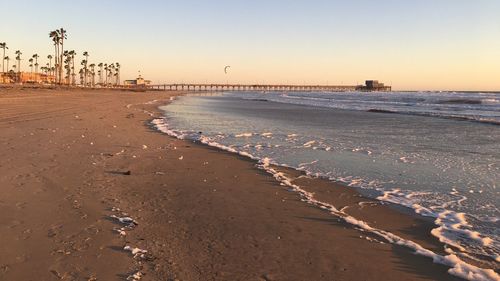 Scenic view of beach against clear sky during sunset