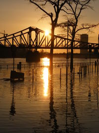Silhouette bridge over river against sky during sunset