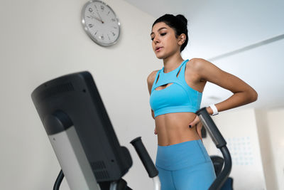 Young woman training at the gym using eliptical crosstrainer