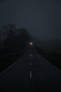 Road amidst trees against sky at night