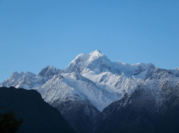 Scenic view of snowcapped mountains against clear blue sky