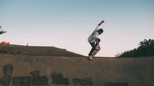 Full length of man skateboarding on sports ramp against clear sky during sunset