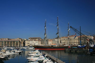 Sailboats moored at harbor against clear blue sky