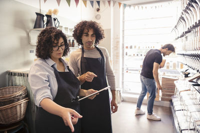 Male and female entrepreneurs discussing over tablet while customer shopping at organic store