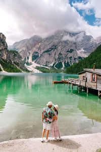 Rear view of women standing on lake against mountains