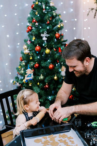 Side view of man holding christmas tree at home